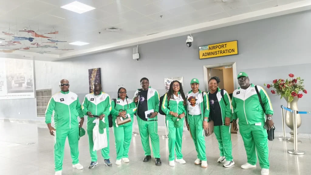 Delegation members in coordinated green tracksuits at an airport.